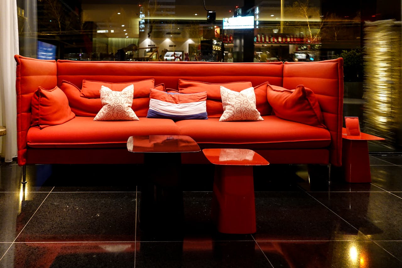 about-02 Elegant red sofa with pillows in a stylish nightclub setting, perfect for nightlife ambiance.